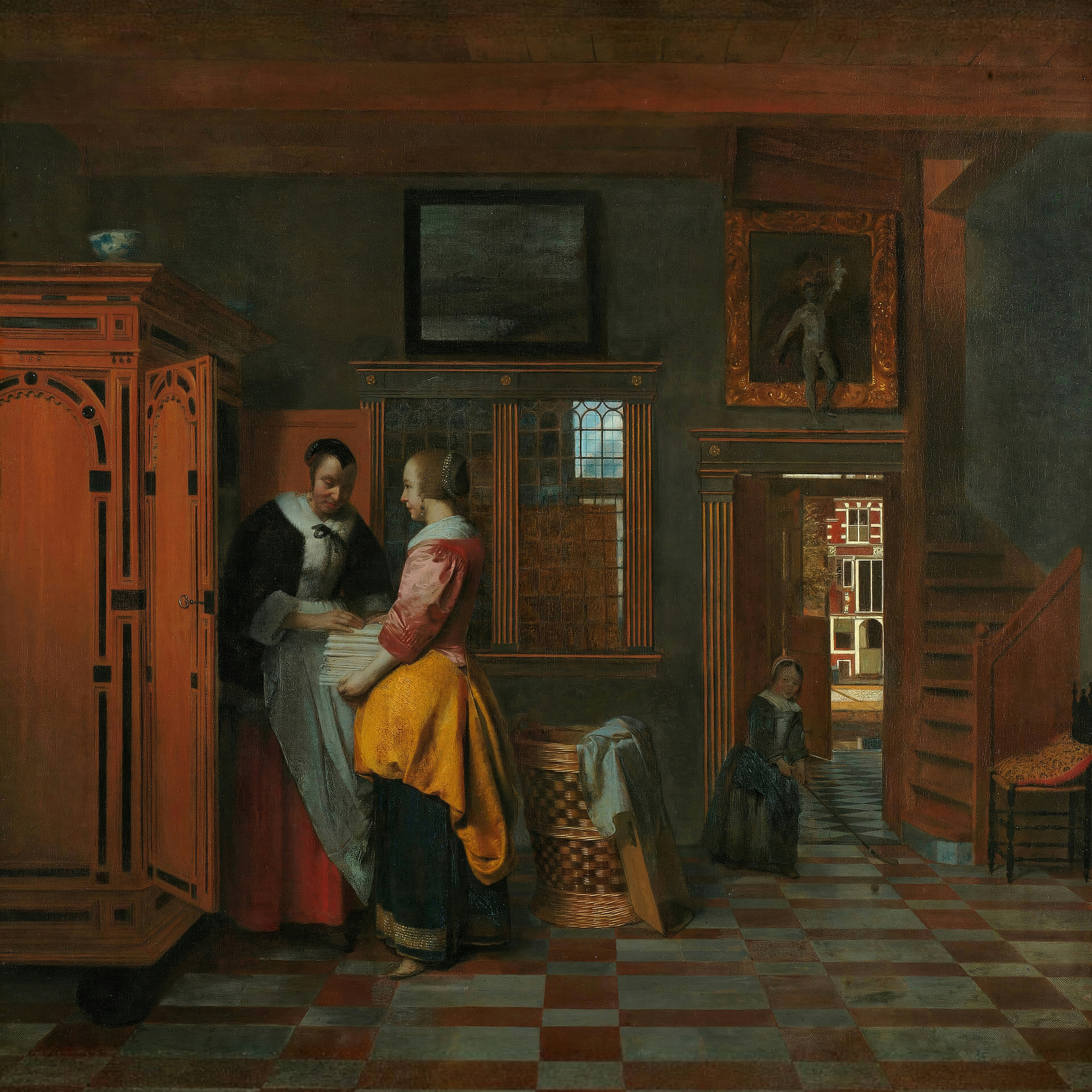 Two women fold white linen beside a tall carved cupboard while a child plays in a doorway that opens onto a sunlit street.