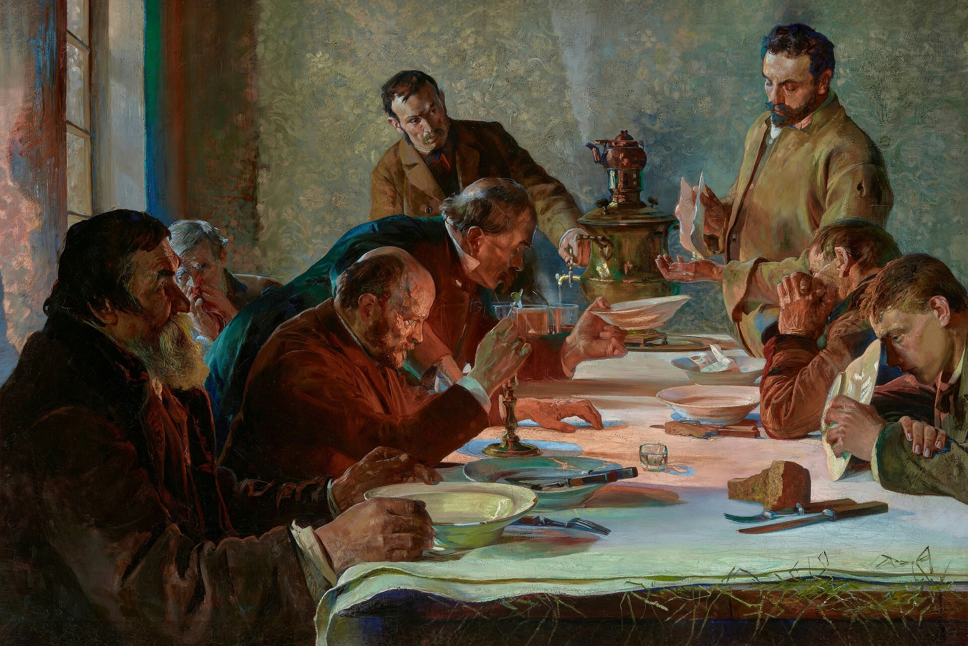 Men in heavy coats gather around a long table with a white cloth in a bare room on Christmas Eve.