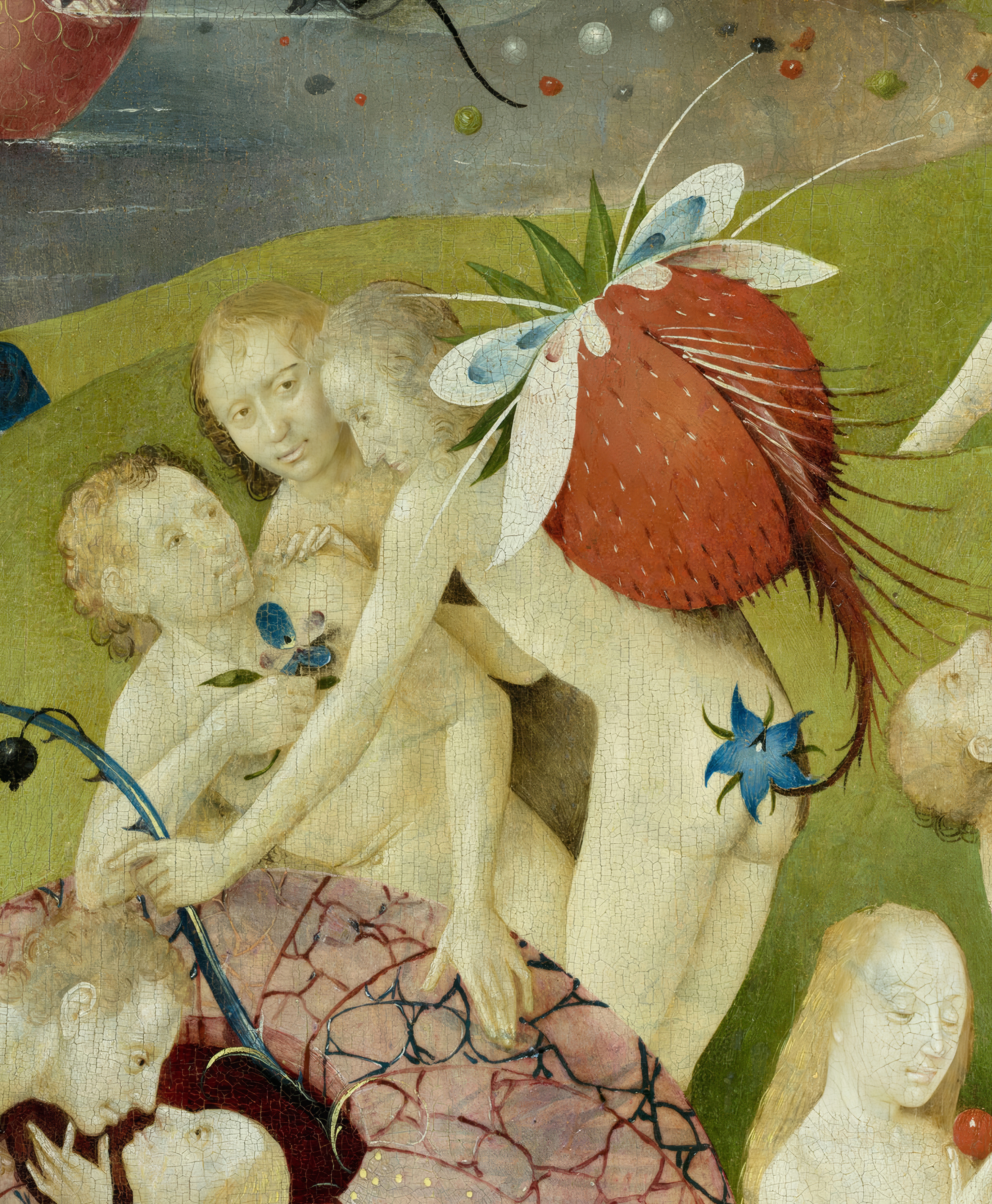 Pale nude figures embracing a giant red strawberry in the green garden of pleasures; detail of Bosch's Garden of Earthly Delights.