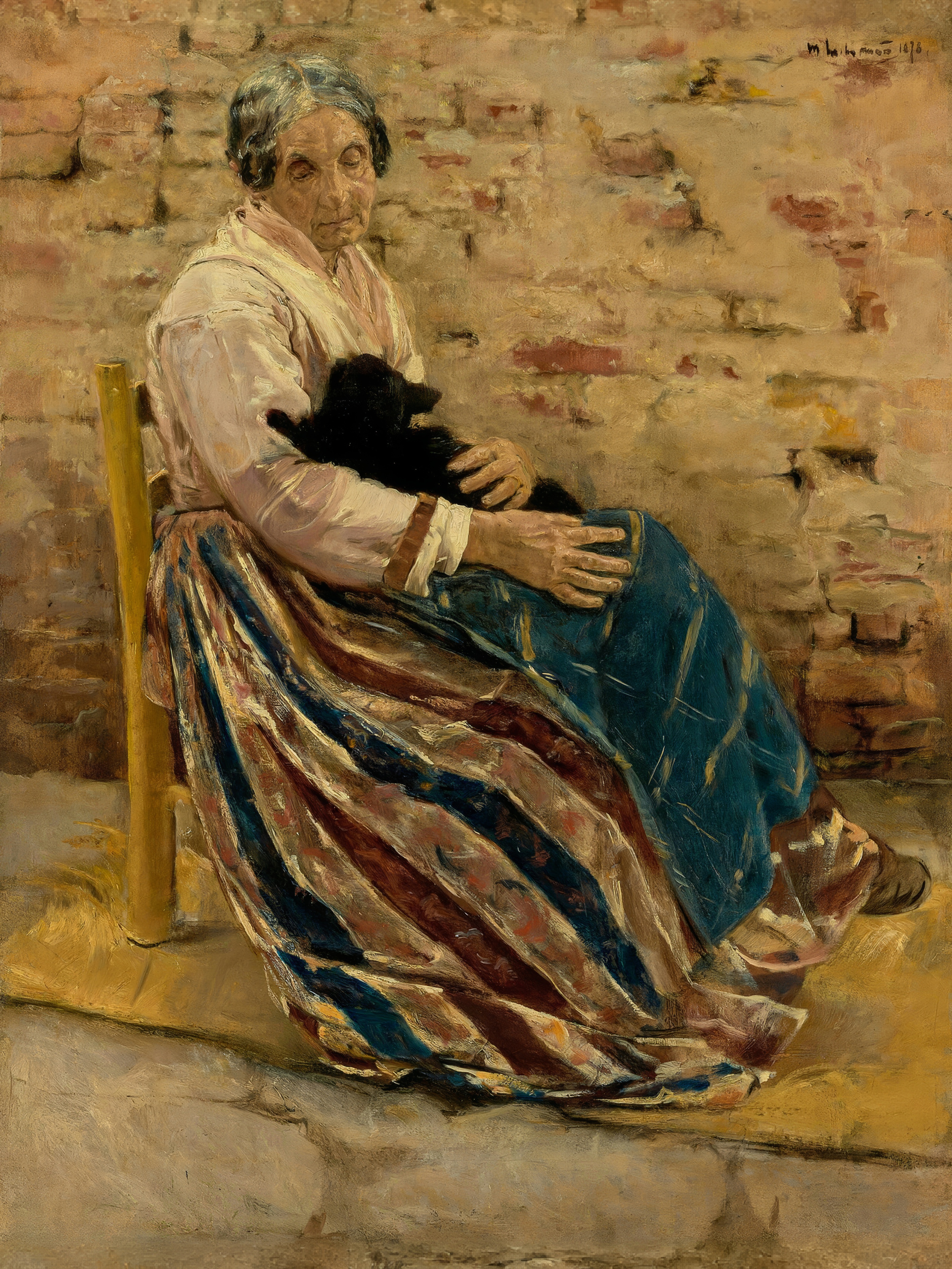 An older woman sits against a brick wall with a dark cat asleep in her lap.