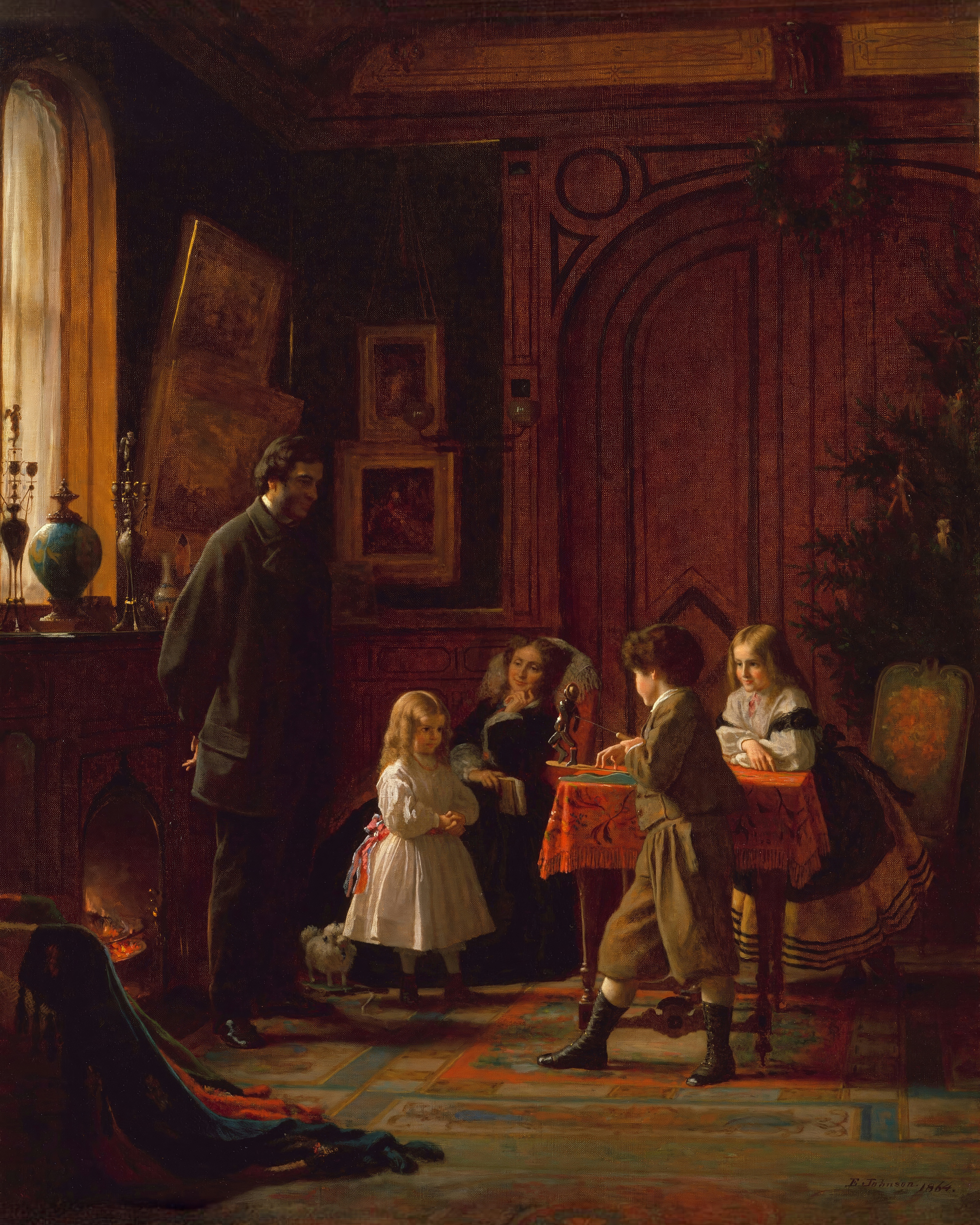A family gathers around a red covered table by the fire at Christmas.