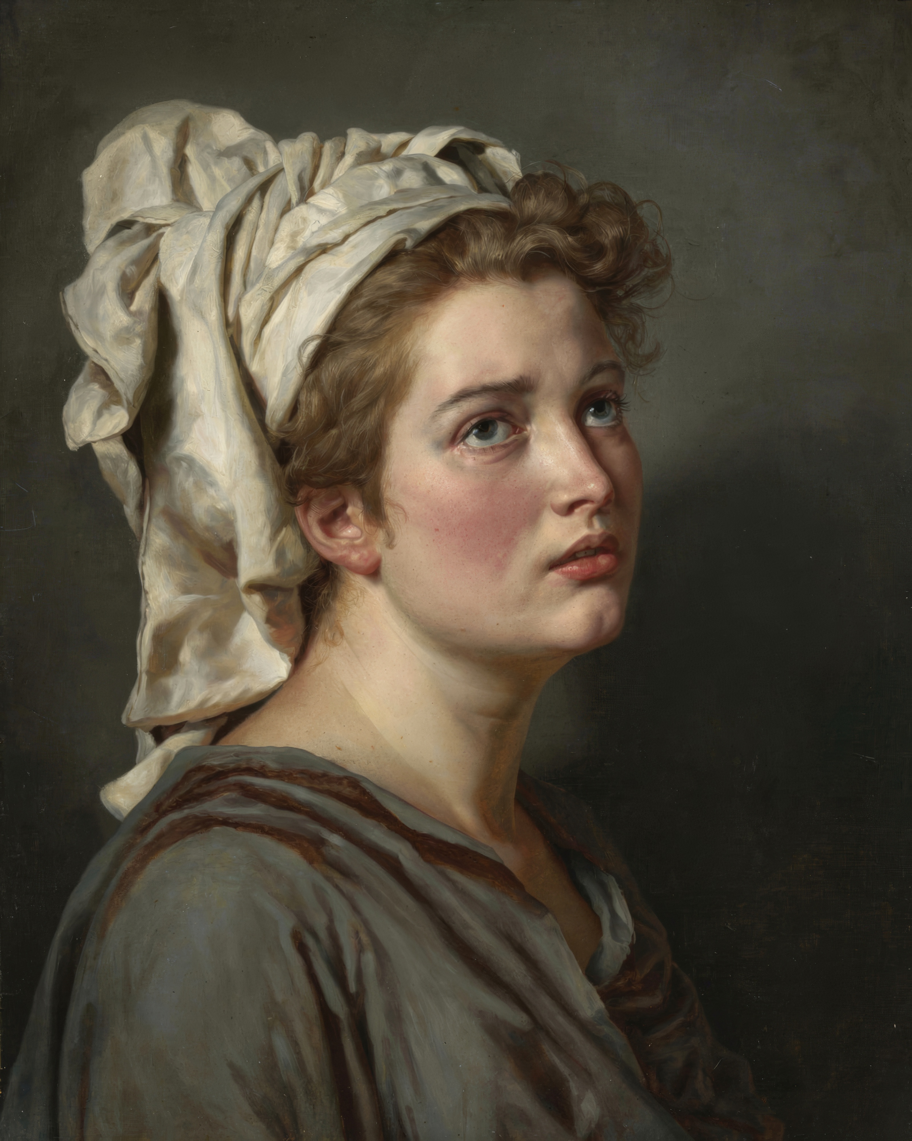 A young woman wearing a soft white turban looks thoughtfully past the viewer.