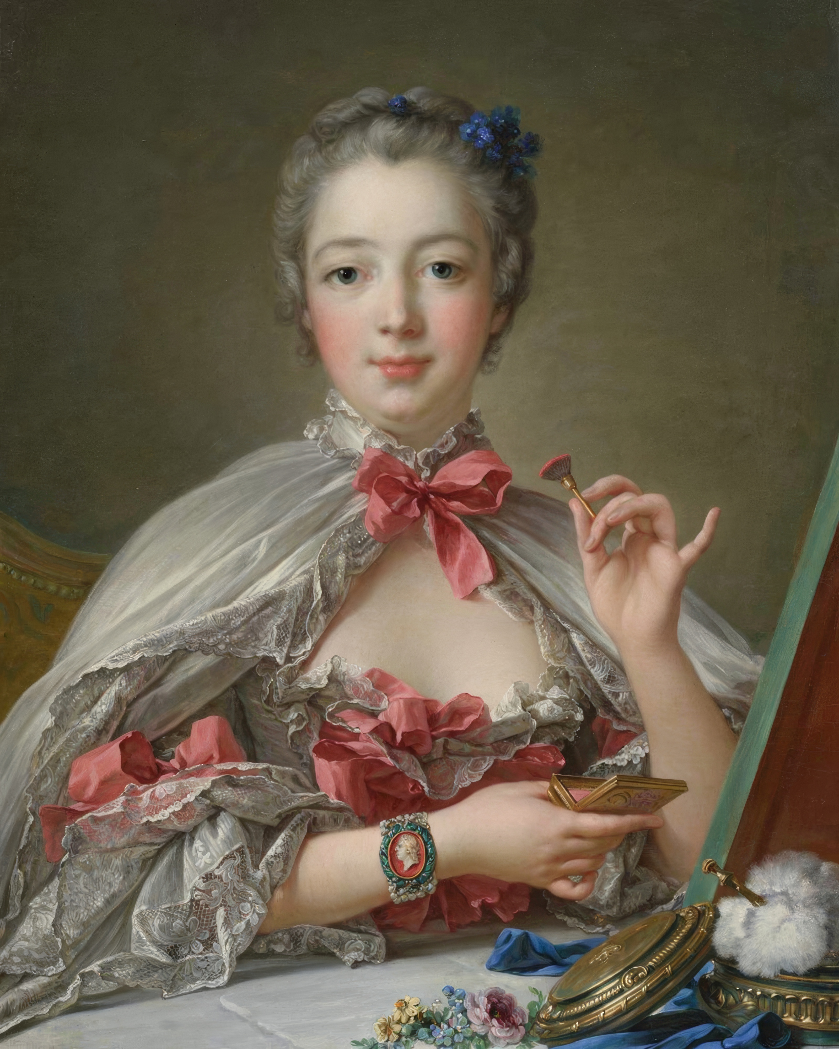 Madame de Pompadour in a silk gown sits at her dressing table and looks at the viewer.