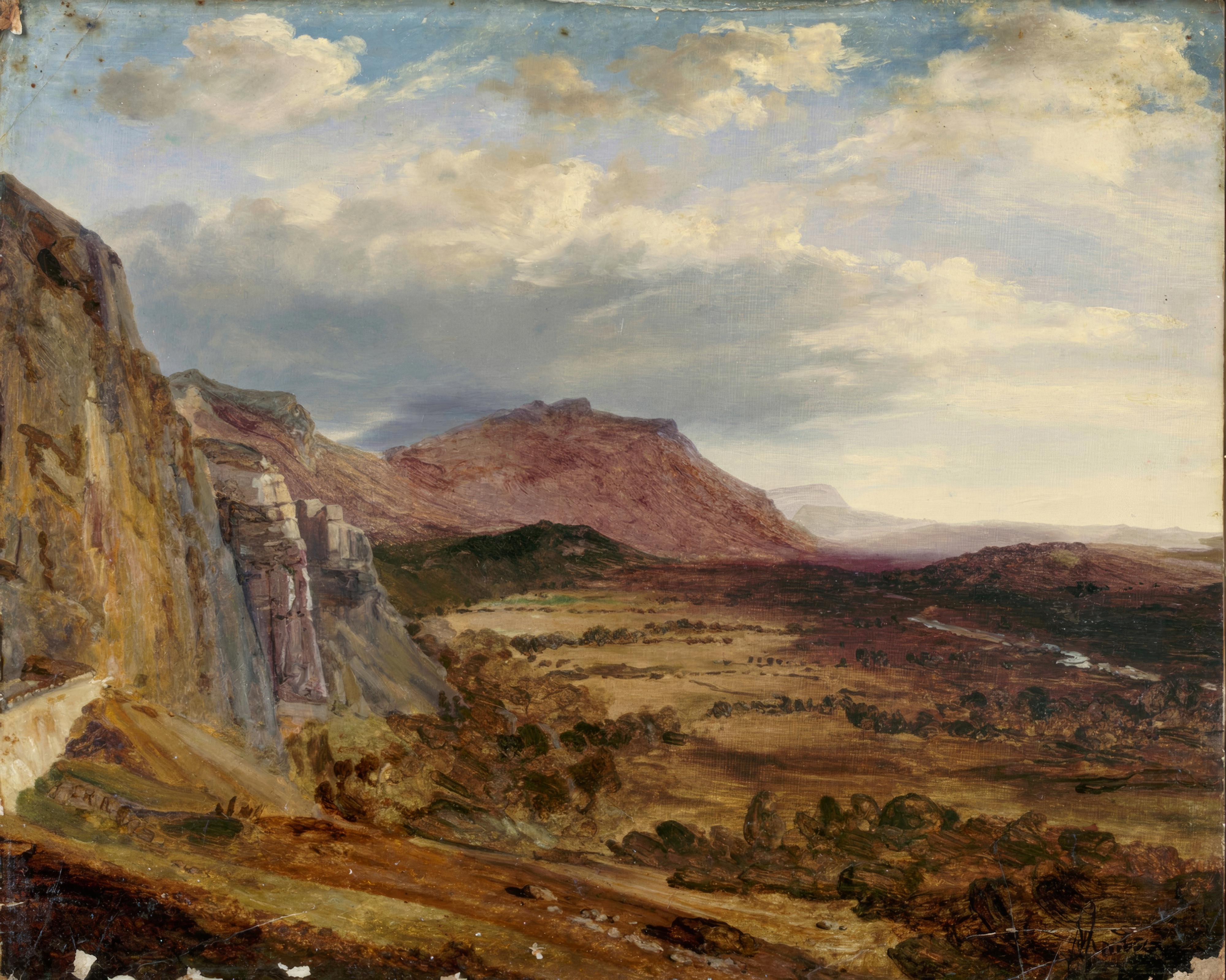 A wide valley under a dramatic sky, with a long mountain ridge and a small figure on a path.