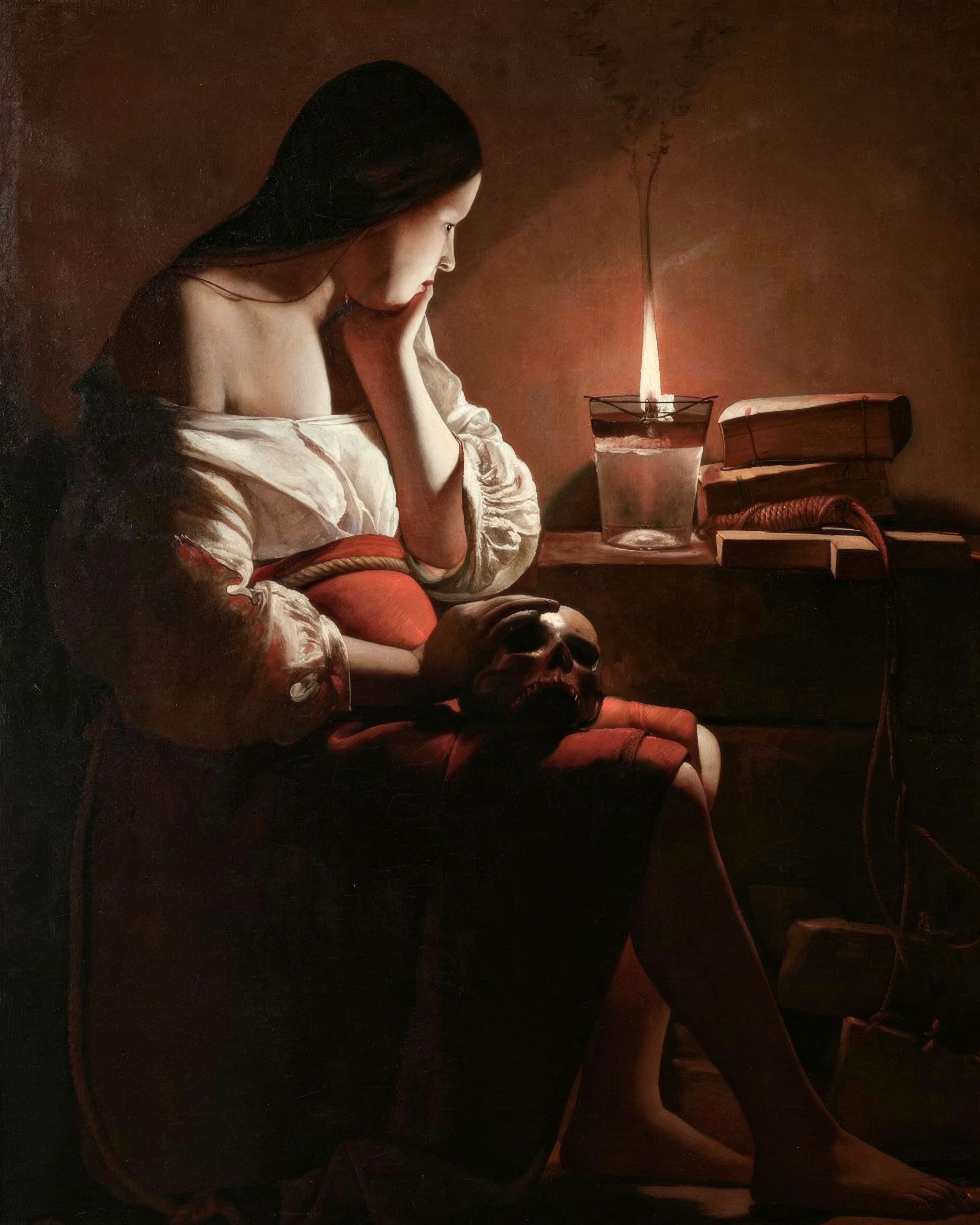 Mary Magdalene sits by a candle in the dark, one hand resting on a skull in her lap.
