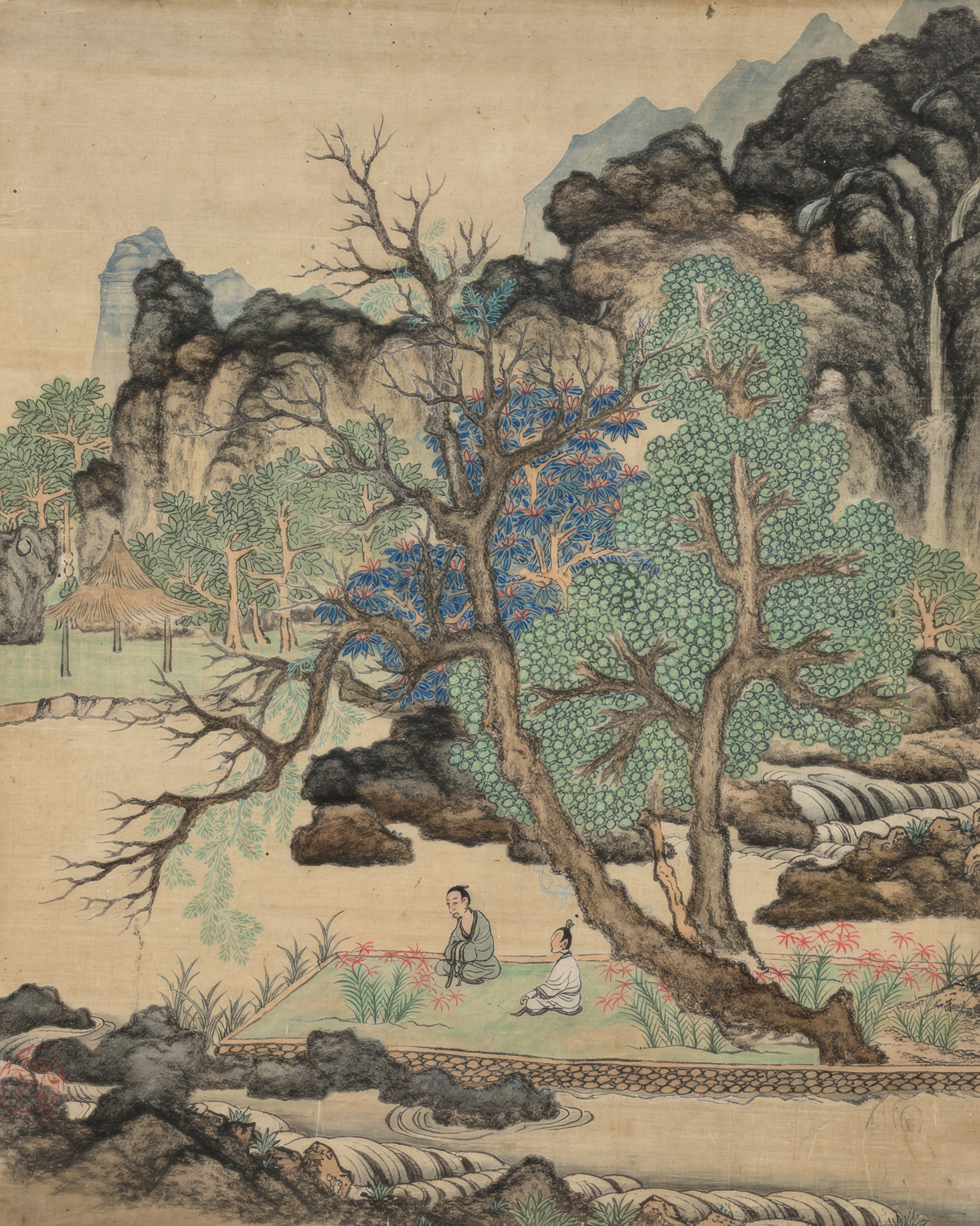 Two scholars sit in quiet conversation among rocks, trees and a garden table, painted on silk.