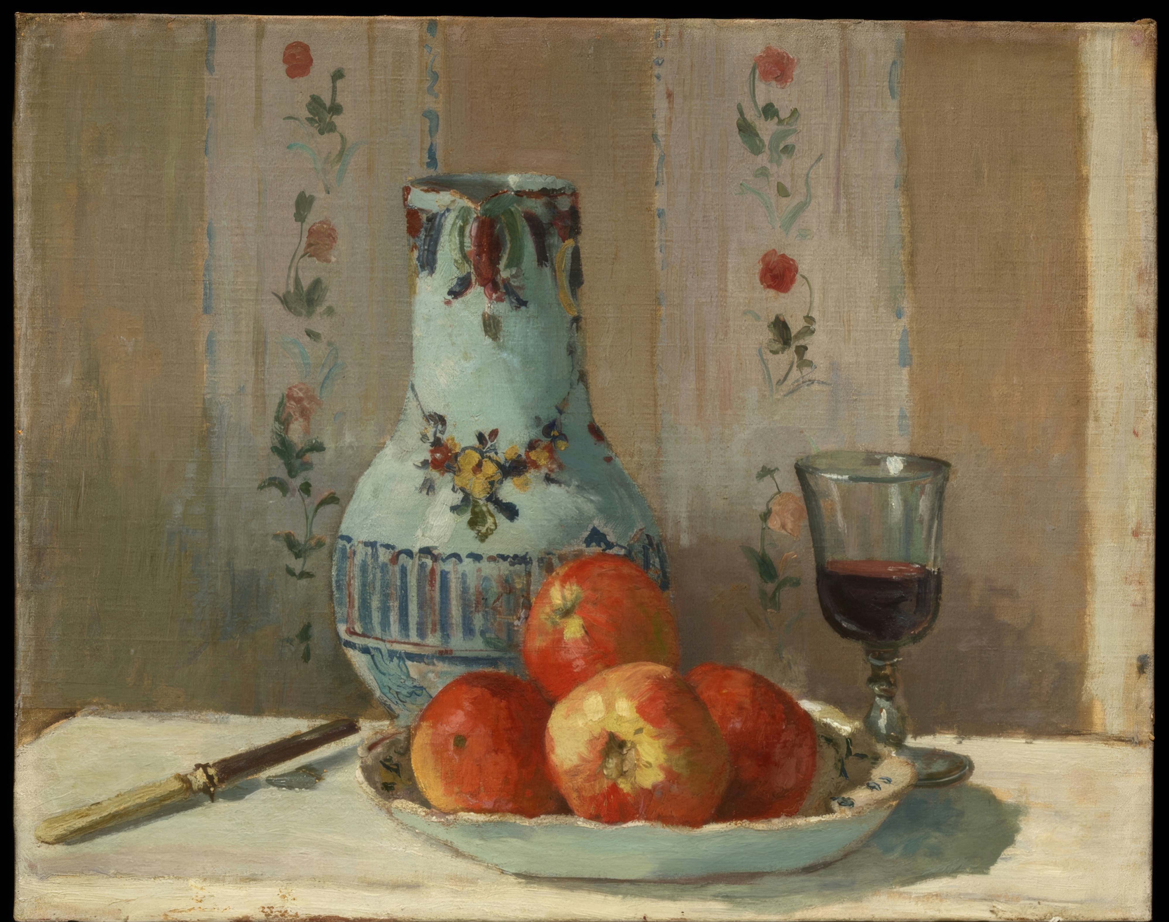 Red apples gather around a white ceramic pitcher with a knife on a wooden table.
