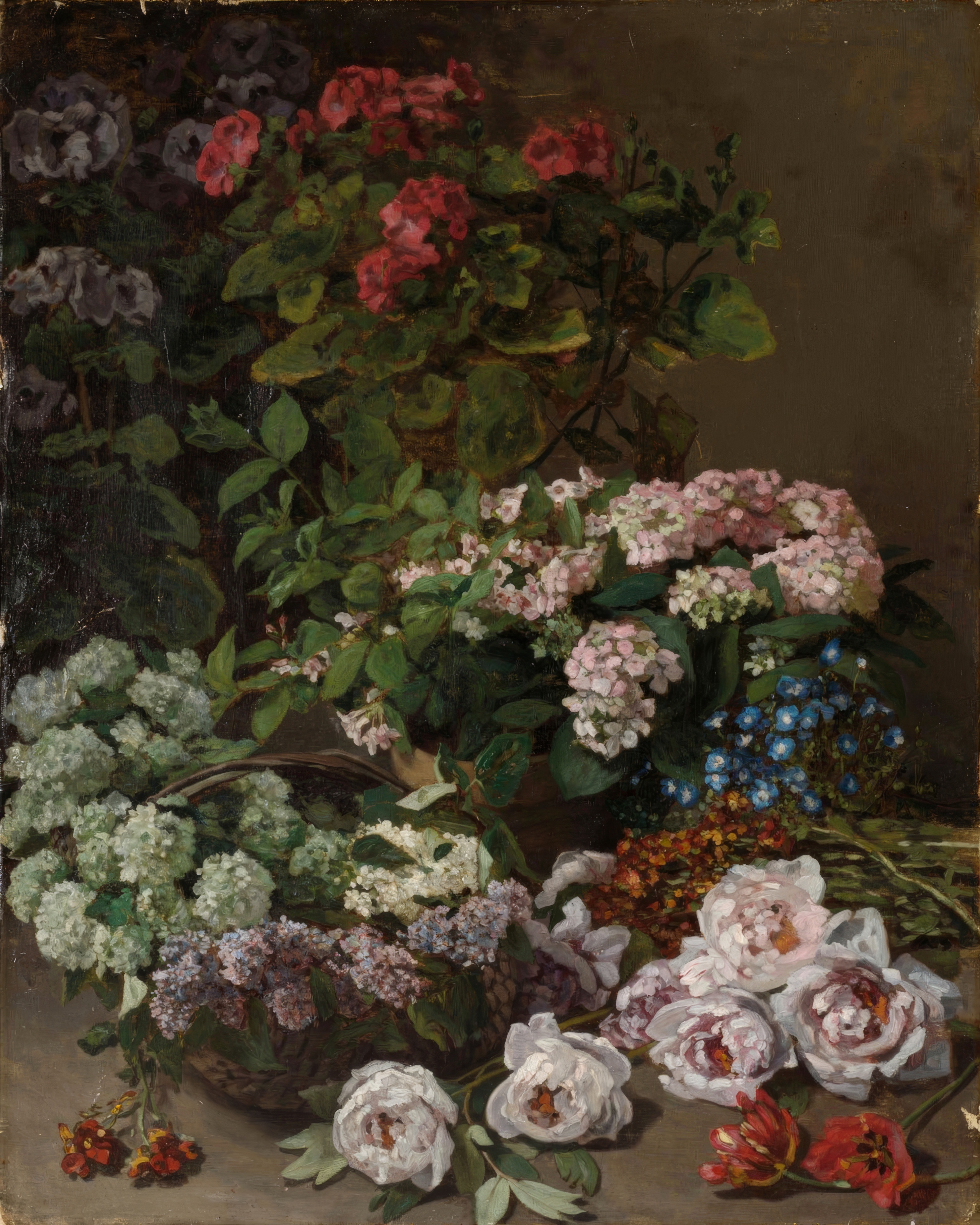 A lush bouquet of lilacs, tulips, peonies and other spring flowers in a basket.