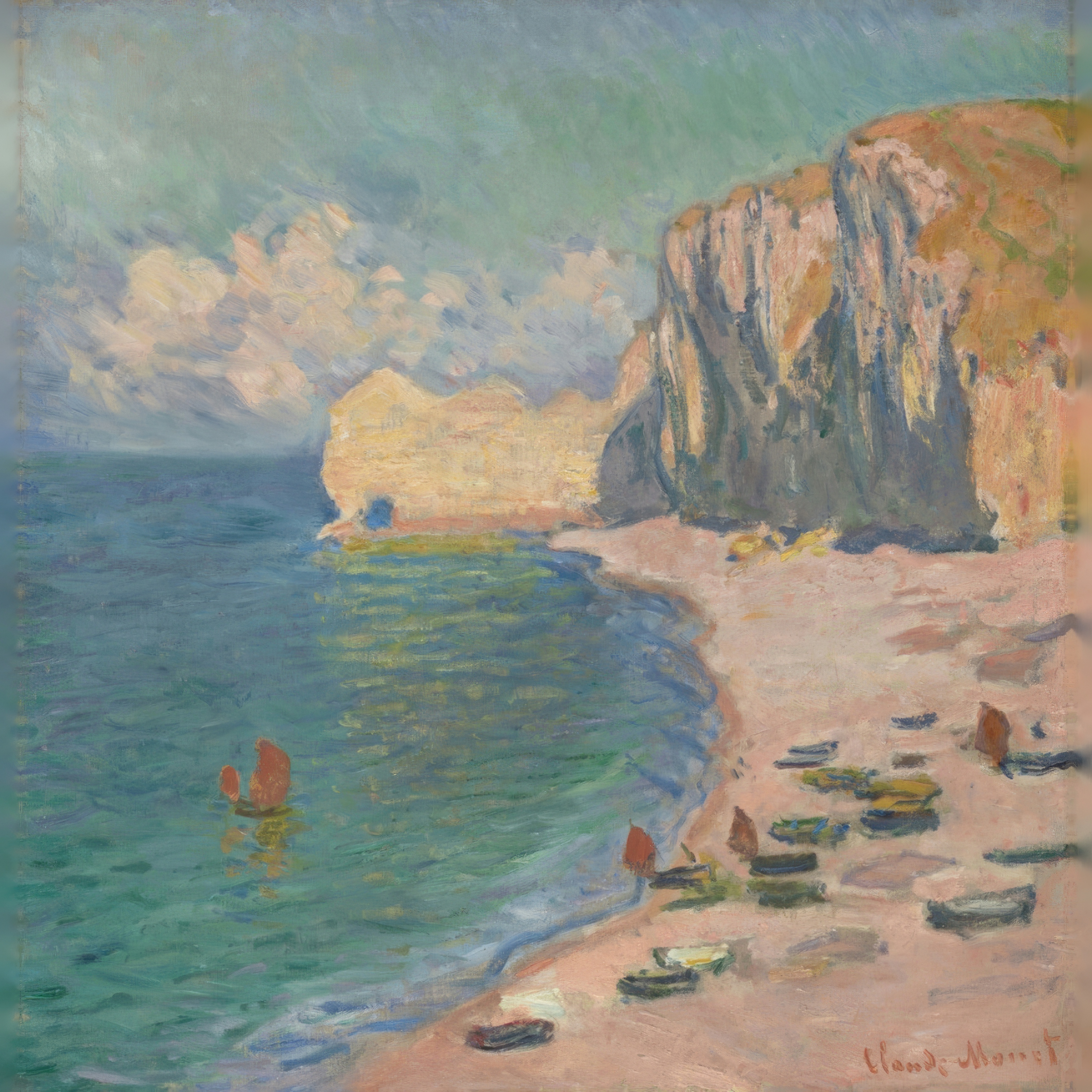 Fishing boats rest on a pebble beach below the white chalk cliff of Étretat, under a pale blue sky.