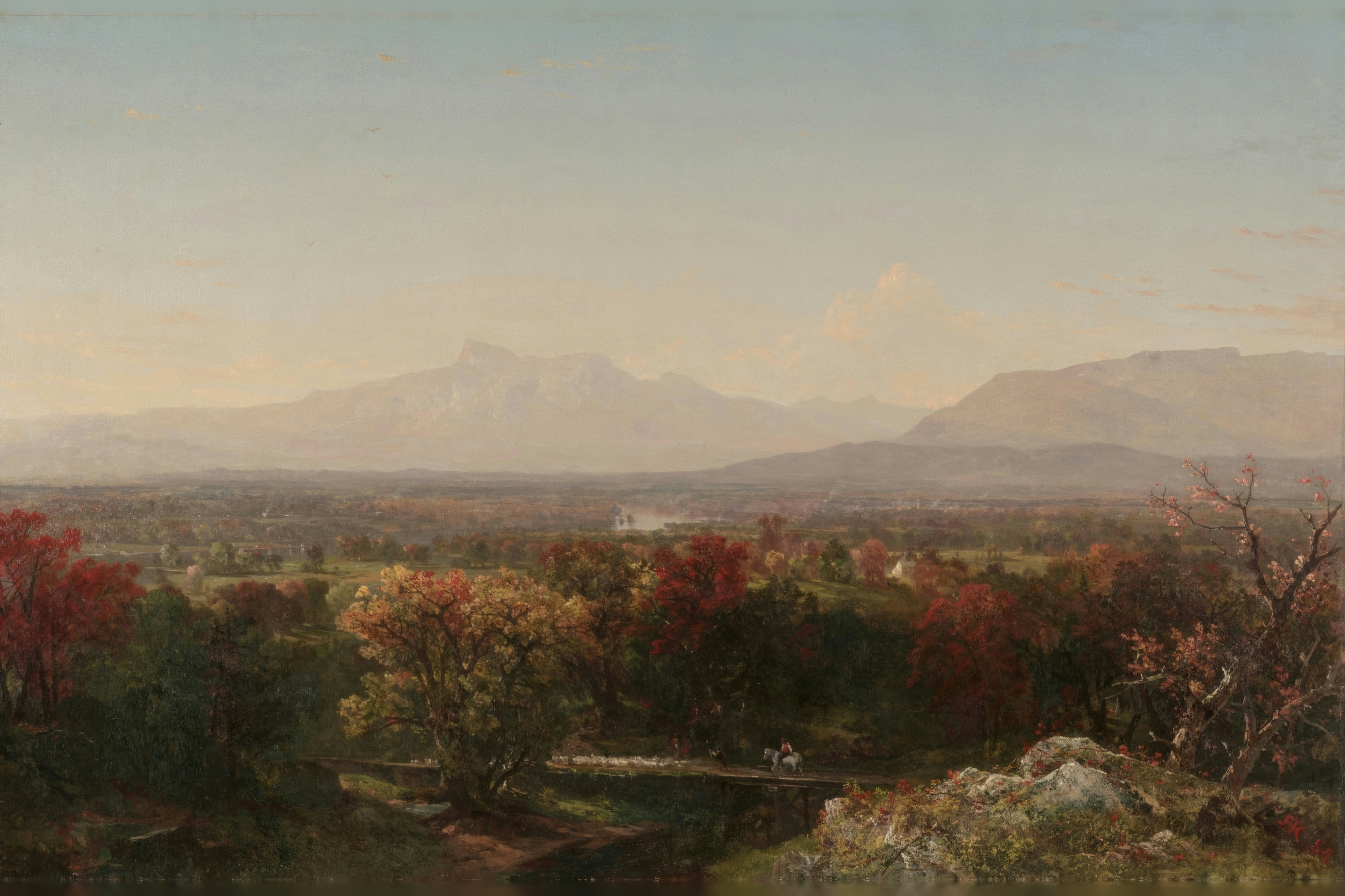A calm lake stretches toward gentle mountain slopes in the warm haze of autumn.