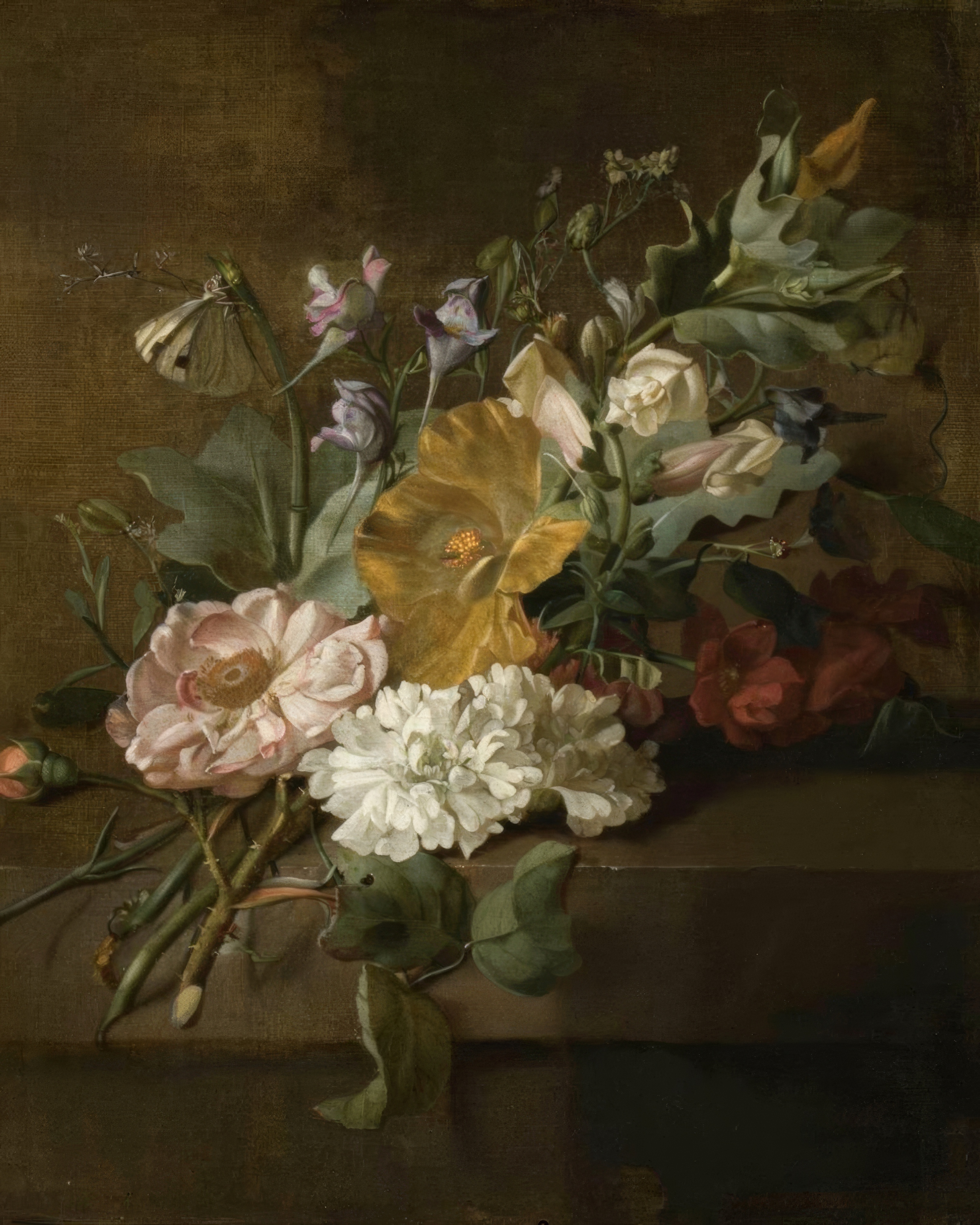 A loose spray of roses, poppies and other flowers spilling from a glass vase onto a stone ledge.